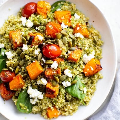 Vibrant roasted butternut squash pesto quinoa grain bowl drizzled with herby green pesto